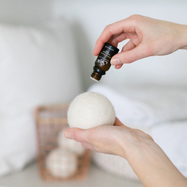 A person dripping the laundry blend onto their wool dryer ball 