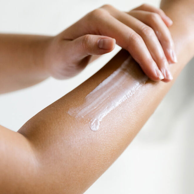 A hand applying lotion to the opposite forearm 