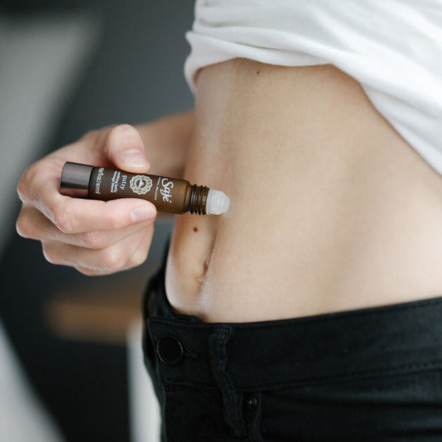 A women applying Gutzy soothing belly blend roll-on 0.34fl oz to their stomach 