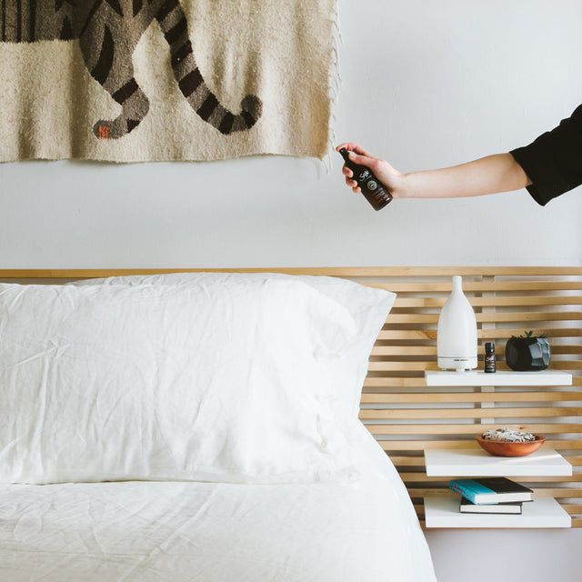 Person misting Sleep Well Mist by bed before sleep