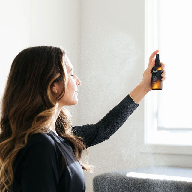 A woman spraying Yoga transition mist into the air 