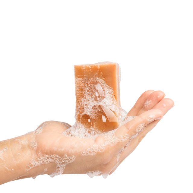 Wet Liquid Sunshine soap bar with lather on it being held upright in a hand